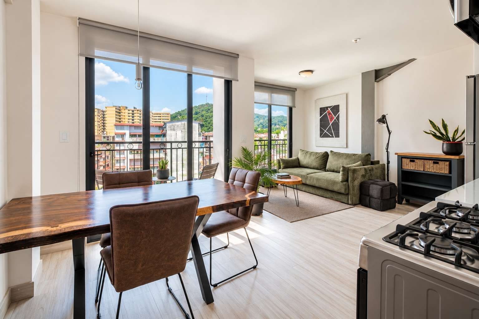 A modern apartment with a dining area, sofa, and kitchen.
