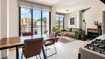 A modern apartment with a dining area, sofa, and kitchen.