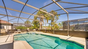 Piscina com cobertura de vidro, rodeada por espreguiçadeiras e um espaço de estar ao ar livre.