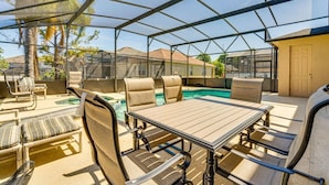 Área externa coberta com piscina, assentos e uma mesa.