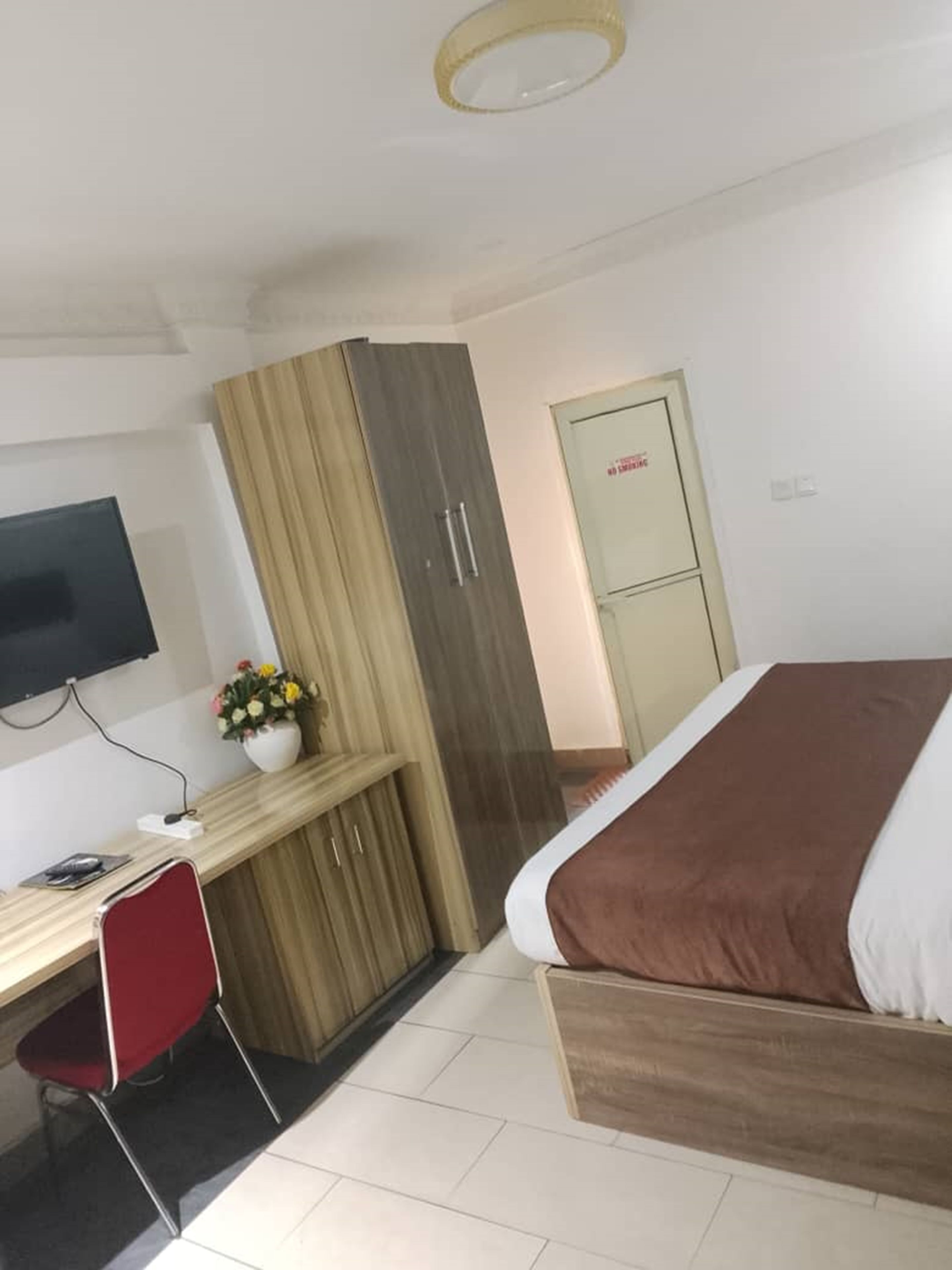 Une chambre d’hôtel comprenant un lit, un bureau avec une chaise, une télévision et une armoire.