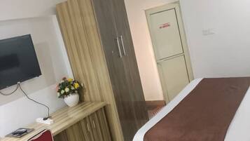 Une chambre d’hôtel comprenant un lit, un bureau avec une chaise, une télévision et une armoire.