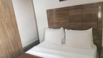 Habitació d'hotel amb un llit, un armari de fusta i un quadre al mur.