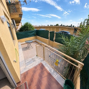 A balcony with a table and chairs, a green plant, and a view of neighboring buildings. - Beach house, 50 meters from the beach.  Your Perfect Spot in Palermo (Palermo)