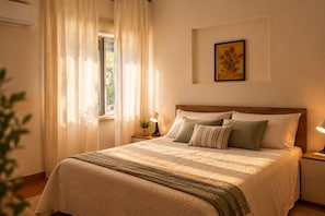 A neatly made bed with a striped blanket, a bedside lamp, and a framed picture on the wall. - Beach house, 50 meters from the beach.  Your Perfect Spot in Palermo (Palermo)