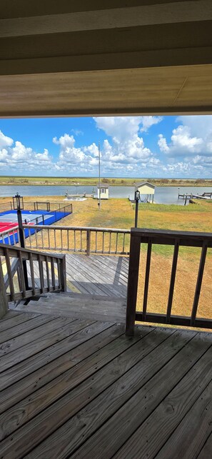 Una terraza de madera con vistas a un lago y un muelle pequeño.