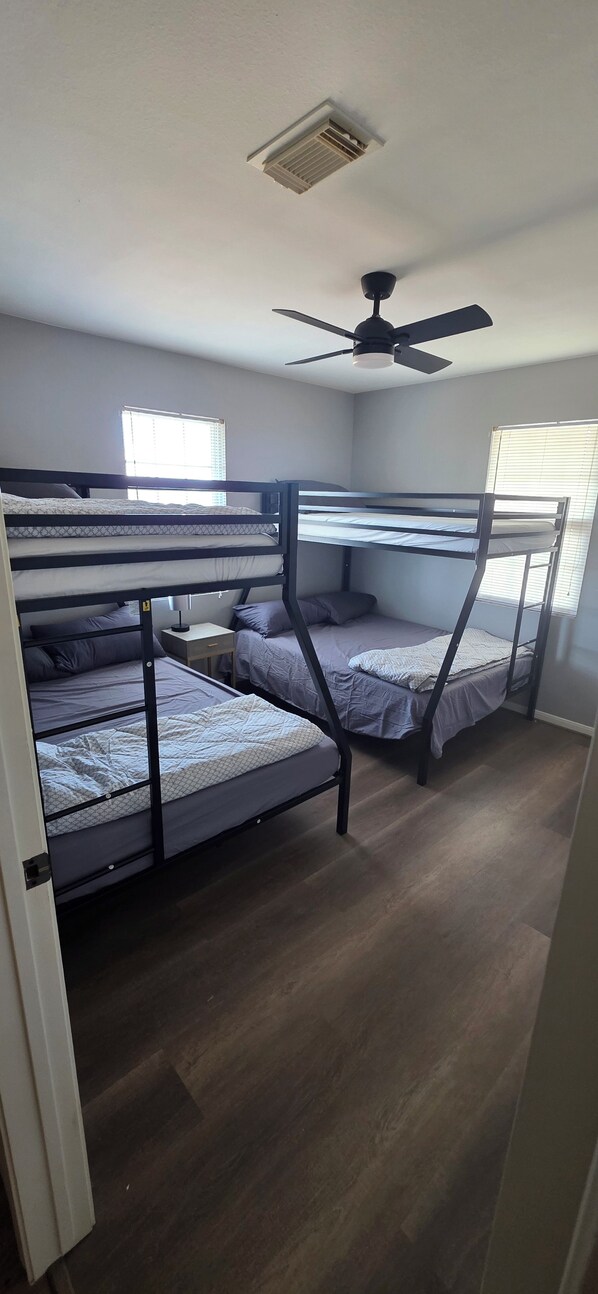 A room with bunk beds, a ceiling fan, and a window with blinds.