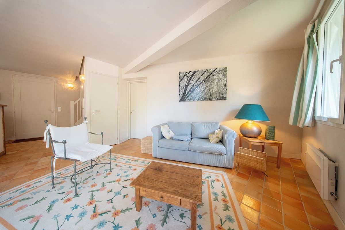 A living room with a sofa, a chair, a coffee table, a lamp, and a painting on the wall.