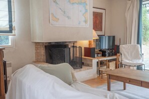 A cozy living room with a fireplace, a sofa, a coffee table, and a television. - Coin de paradis - Grande maison pour 14 pers (Saint-Philibert)