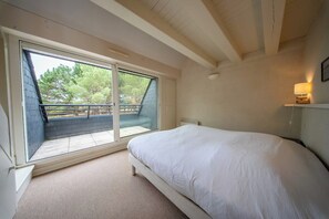 A bedroom with a bed, a window, and a view of a balcony. - Coin de paradis - Grande maison pour 14 pers (Saint-Philibert)