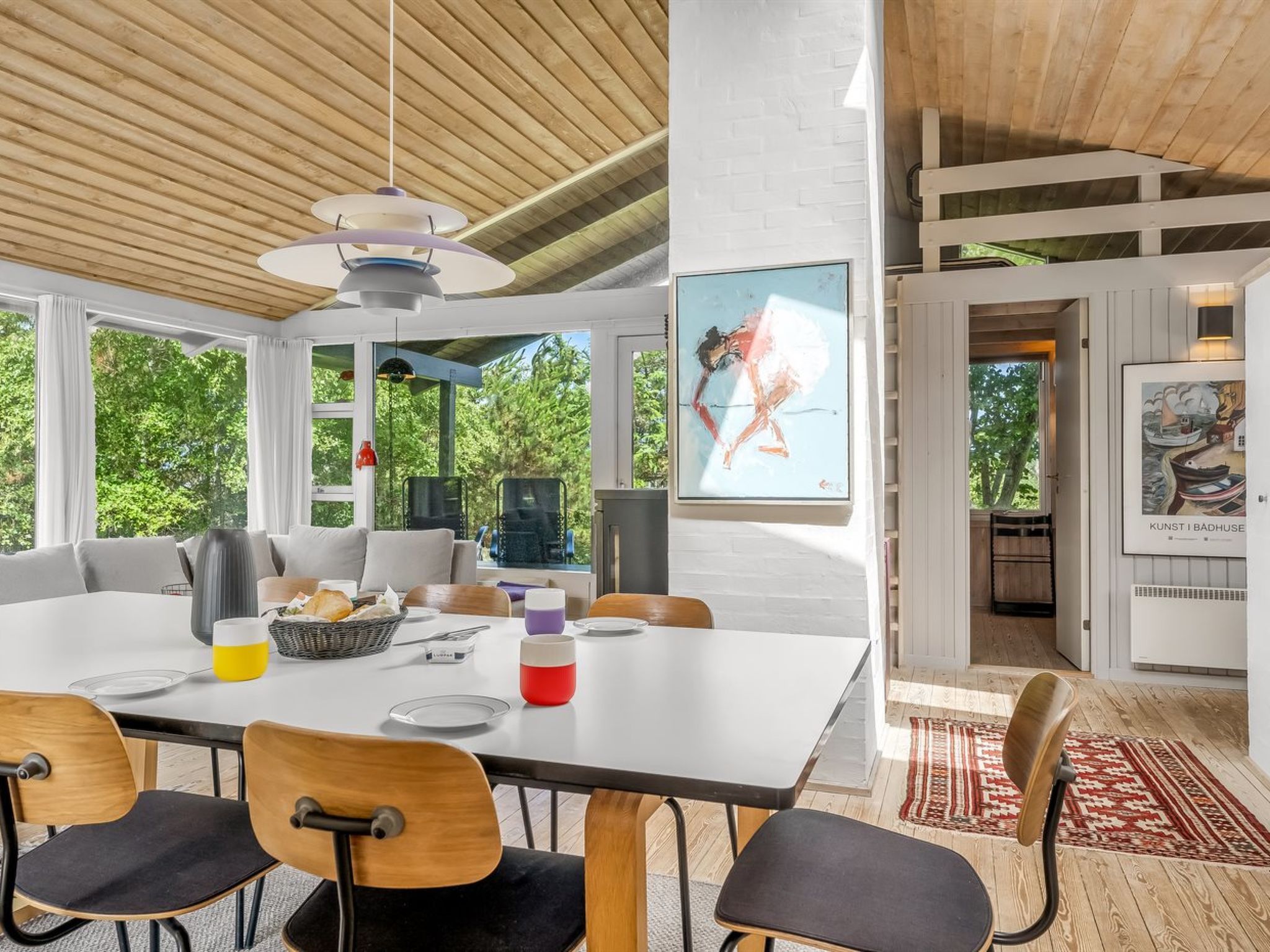 Un comedor moderno con una mesa grande, sillas y vistas al verdor exterior.