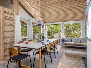 A modern interior with a dining area, seating, and a large window offering a view of greenery. - "Senija" - 100m from the sea by Interhome (Fjerritslev)