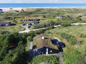 Eine Küstenimmobilie mit mehreren Häusern, einem Strand im Hintergrund und einem klaren Himmel.