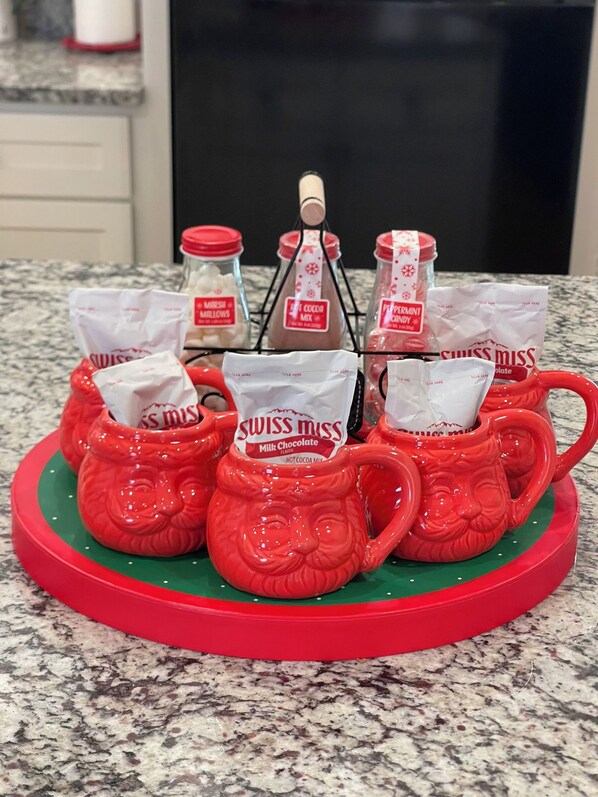 Eine Küchenarbeitsplatte mit einem dekorativen roten Tablett, das Packungen mit Swiss Miss Kakao-Mix und eine Kakao-Mix-Flasche enthält.