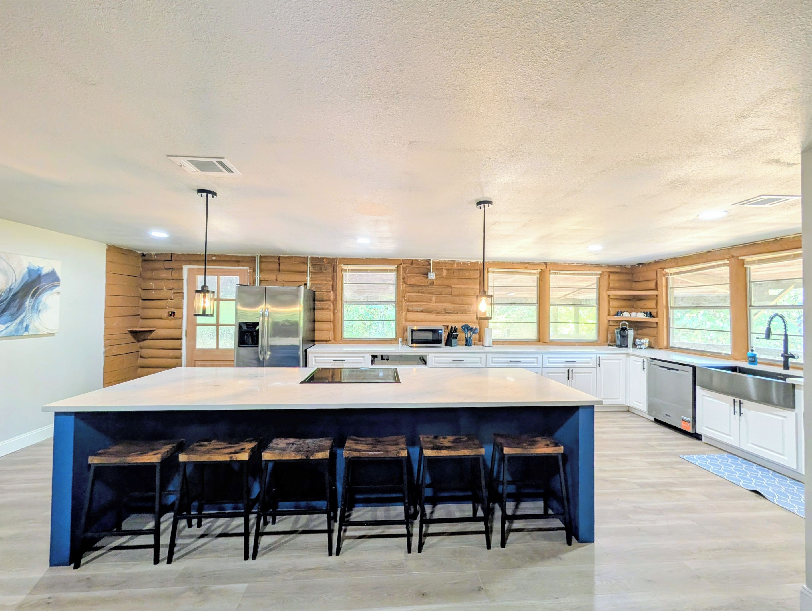 A modern kitchen with a large island, bar stools, and a view of the outdoors.