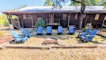 A rustic cabin with a porch and several Adirondack chairs arranged in a semi-circle.