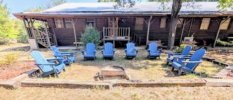 A rustic cabin with a porch and several Adirondack chairs arranged in a semi-circle.