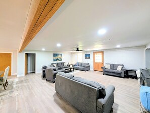 Amplia sala de estar con varios sofás, un comedor y techo de madera.