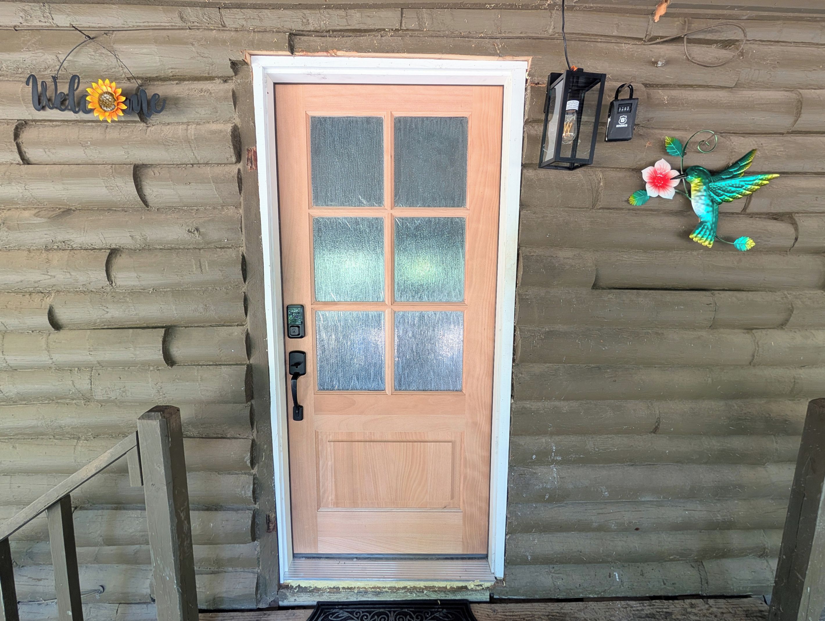 Une porte en bois avec un panneau de verre dépoli, un trou de serrure et un sonnette.
