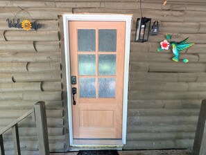 Una puerta de madera con un panel de vidrio esmerilado, un ojo de cerradura y un timbre.