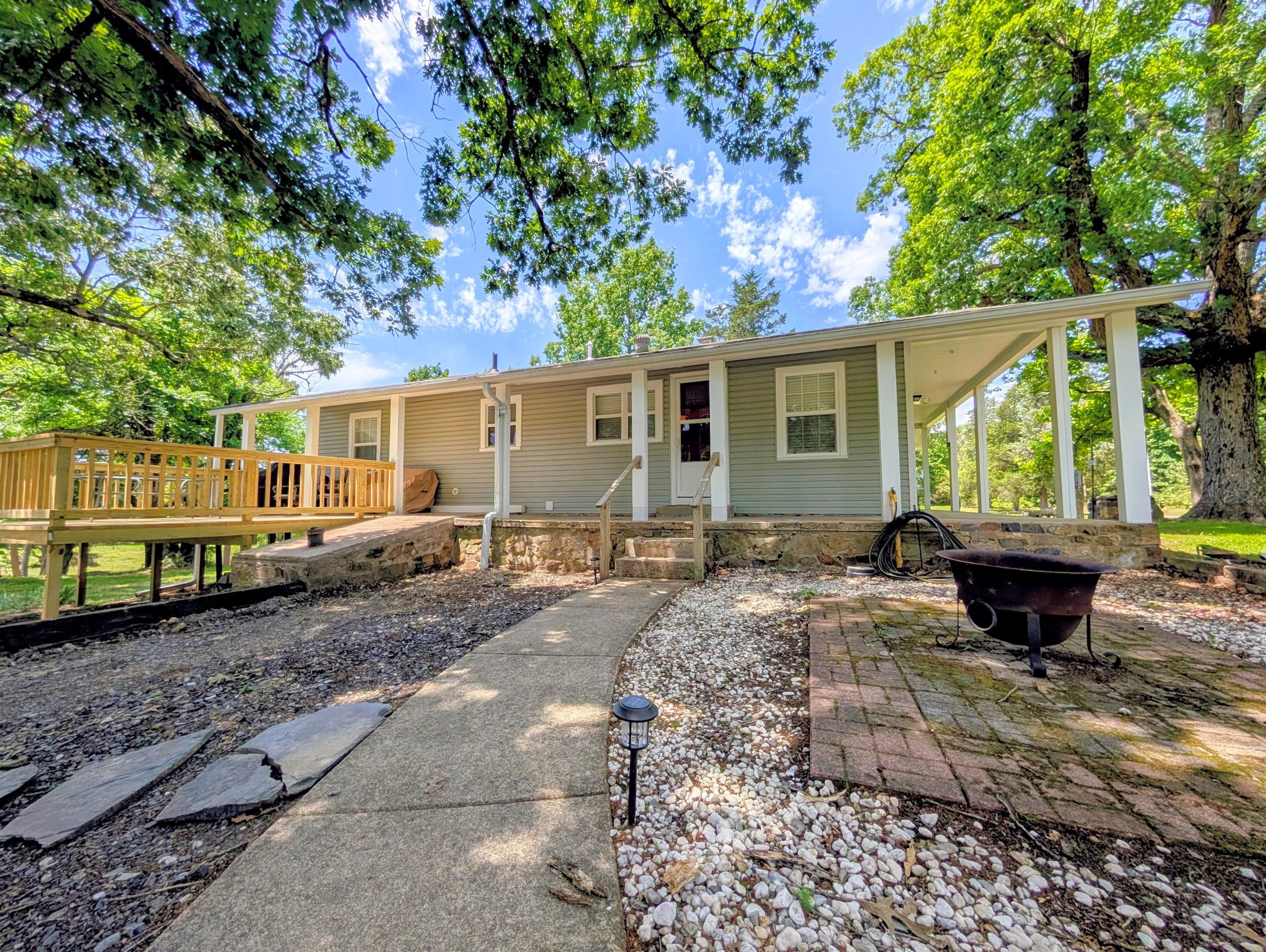 A single-story house with a porch, a deck, and a stone pathway.