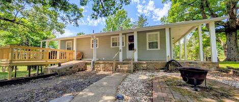 A single-story house with a porch, a deck, and a stone pathway.