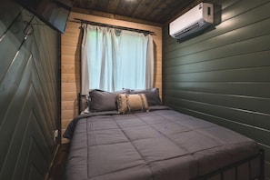 A compact room with a bed, a window with curtains, and an air conditioning unit mounted on the wall. - Pretty in the Pines- *Near WPG* (MENA)