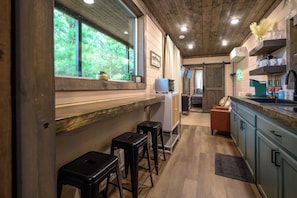 A kitchen with wooden cabinets, a countertop, and a view of the outdoors. - Pretty in the Pines- *Near WPG* (MENA)