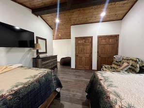 A bedroom with two beds, a dresser, a mirror, and wooden doors. - Whispering Pines - Side by Side Cabins in Shady! (Mena)