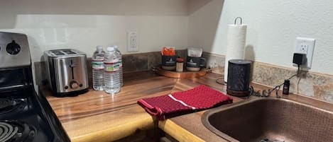 Une cuisine équipée d’une cuisinière, d’un grille-pain, de bouteilles d’eau et d’un évier.