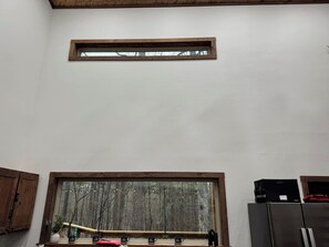 A kitchen with a large window, wooden cabinets, and a stainless steel refrigerator. - Whispering Pines - Cabin by Shady Trails! (Mena)