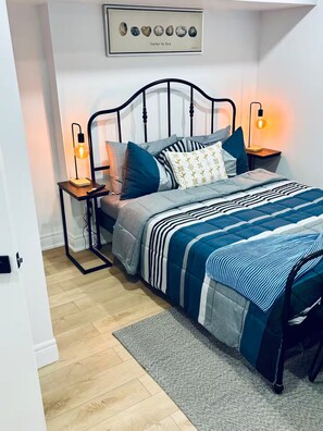 A bedroom with a bed, bedside tables, a rug, and a wall art piece. - Private Bsmt Apt W/Separate Entry- 1 Min to Subway (Oak Park)