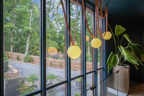 Une pièce dotée de grandes fenêtres, d’une plante en pot et de luminaires sphériques suspendus.