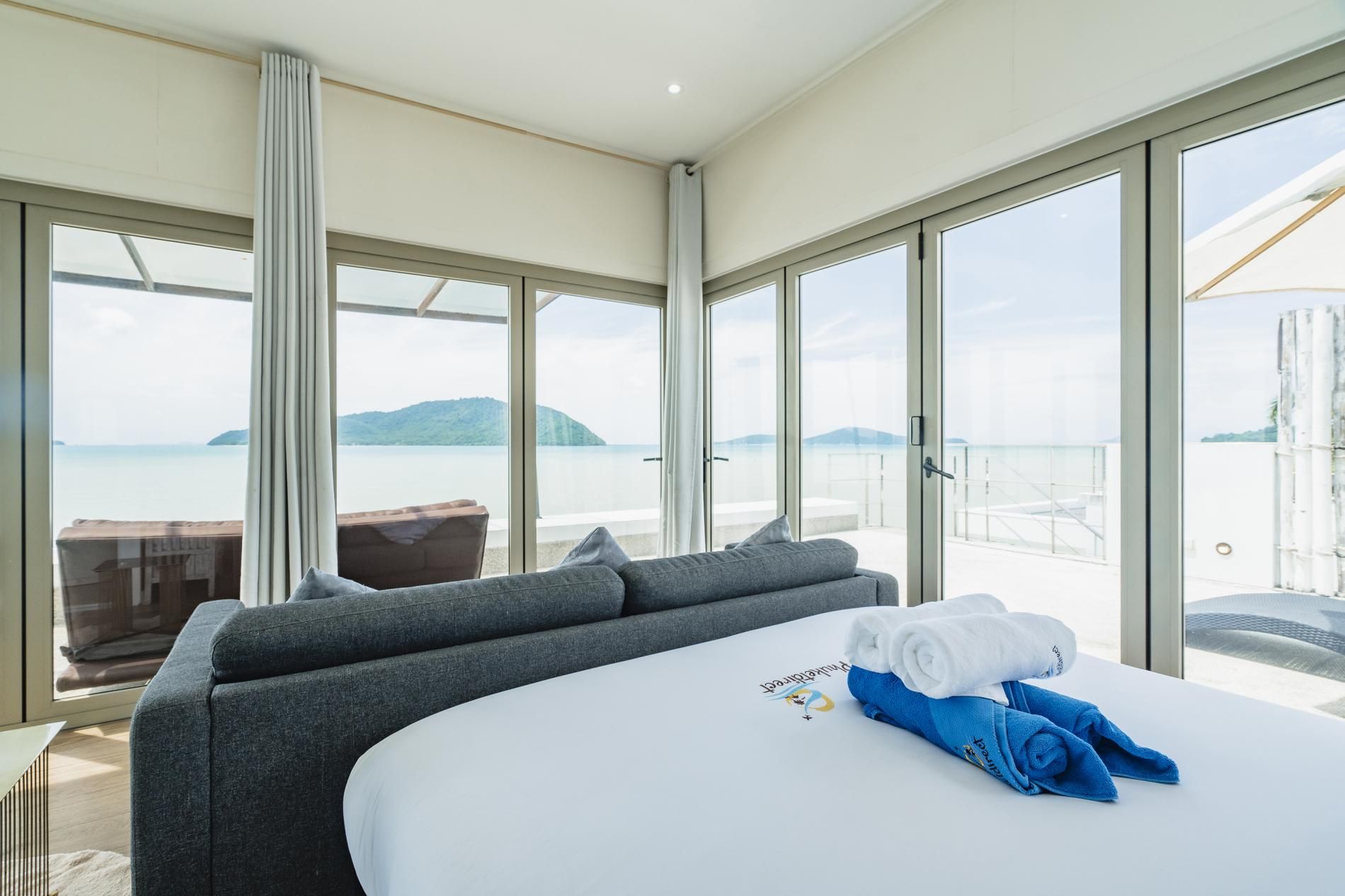 A modern room with a large bed, a sofa, and a view of the sea.