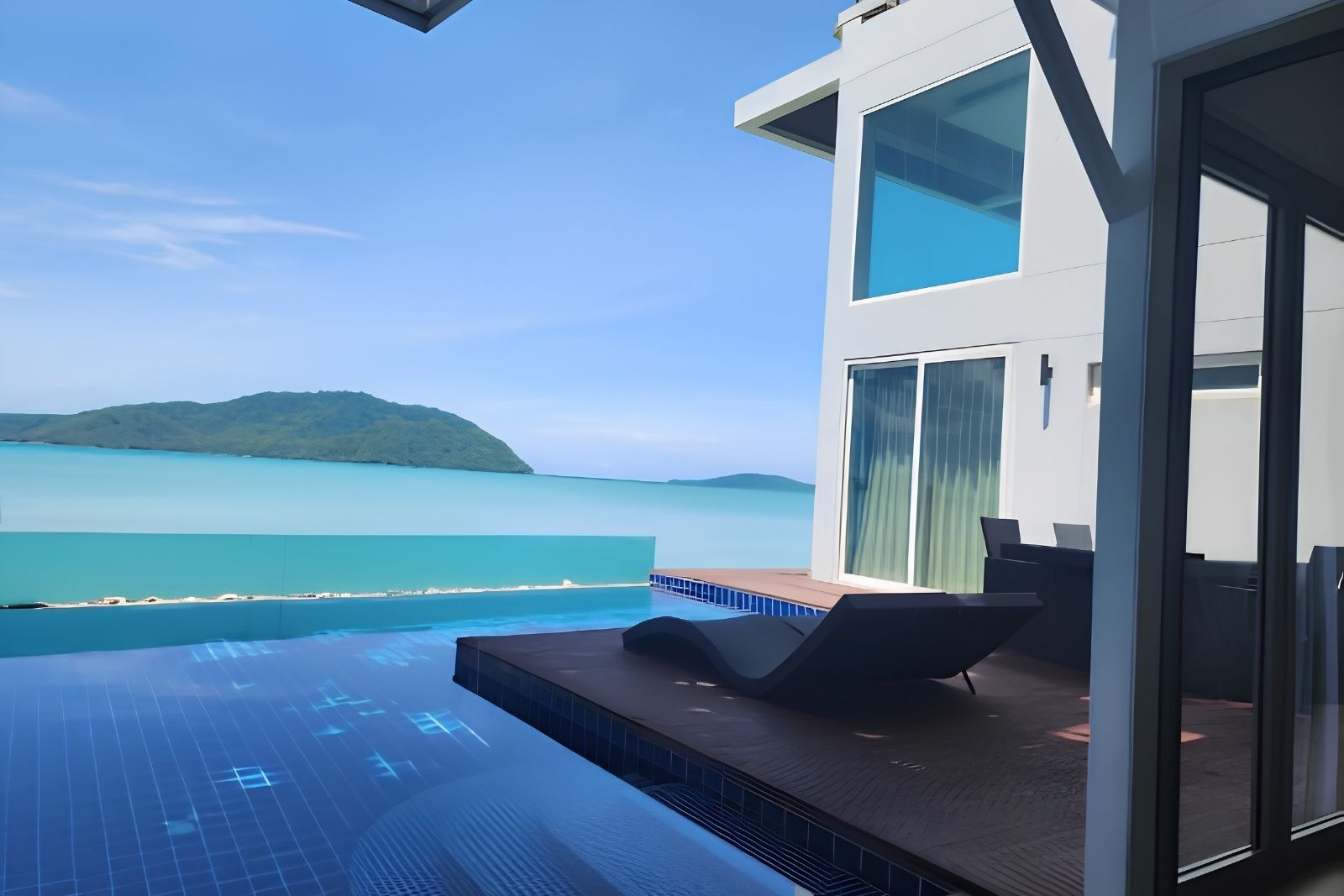 A modern building with a glass door, a pool, and a view of the sea and a distant island.