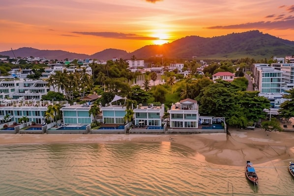 Ein Küstenort mit modernen Gebäuden, einem Strand und einem Sonnenuntergang.
