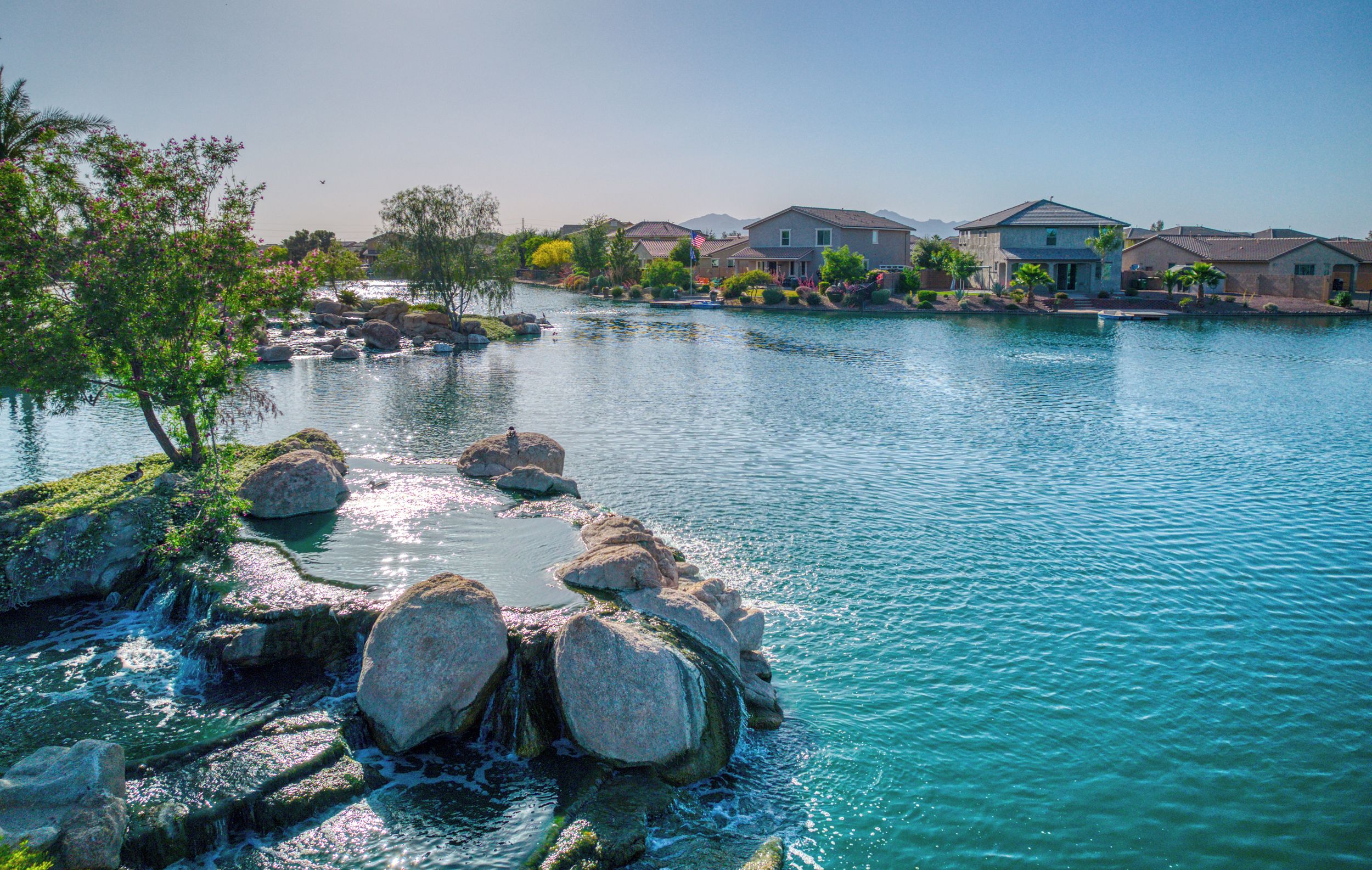 A residential area with a body of water, rocks, and houses.
