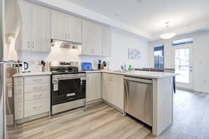 Eine moderne Küche mit weißen Schränken, Edelstahlgeräten und Holzboden.
