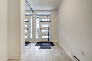 A hallway with a double door, a doormat, and a light switch on the wall. - Luxury 3BR Retreat in South Barrie • Parking (Barrie)
