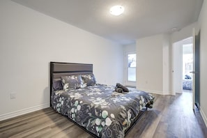 Ein Schlafzimmer mit einem großen Bett, einem Fenster und einer Tür zu einem anderen Raum.