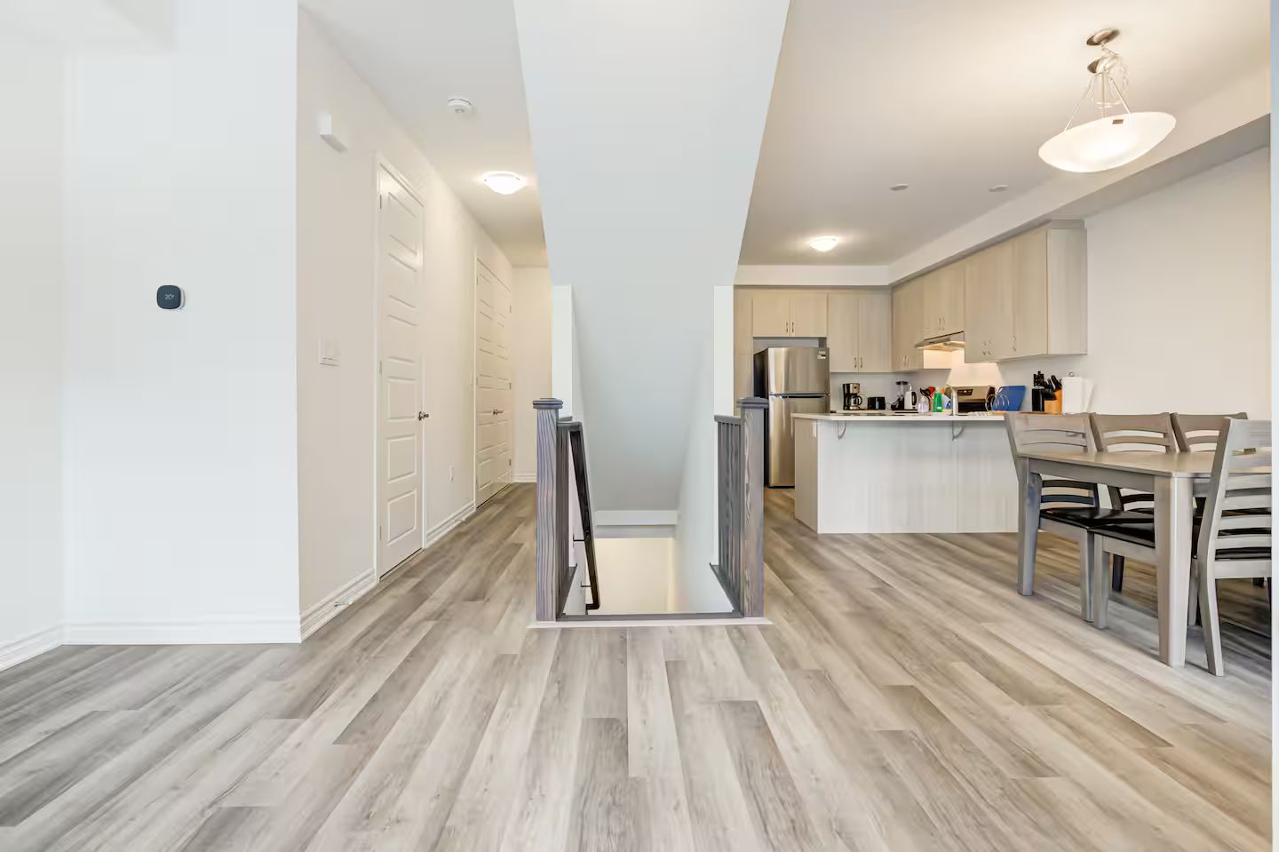Une cuisine moderne dotée d’un îlot central, de meubles blancs et d’un réfrigérateur en acier inoxydable.