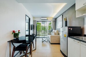 Een moderne keuken met een eethoek, een bank en een balkon met uitzicht op groen.