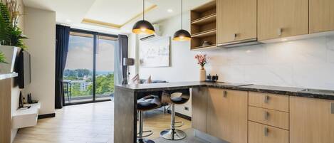 A modern kitchen with wooden cabinets, a marble countertop, and pendant lighting.