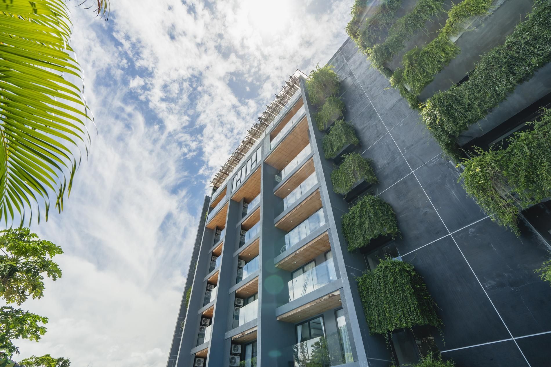 Un immeuble moderne à plusieurs étages, doté de nombreux balcons et d’un jardin sur le toit.