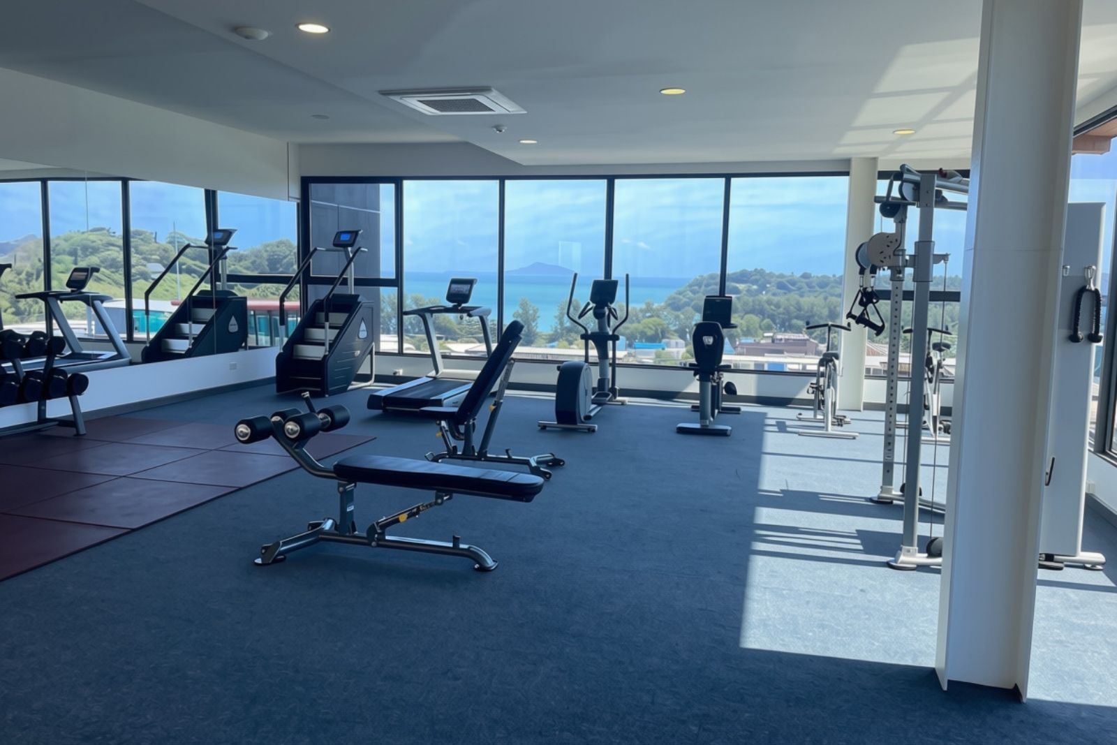 A gym with cardio equipment, weight machines, and a view of the outdoors.
