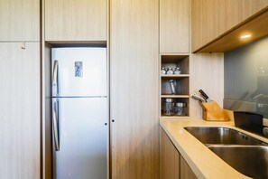 A kitchen with wooden cabinets, a stainless steel sink, and a refrigerator. - At The Tree Sea View 1BR Walk To Rawai Beach (Rawai)