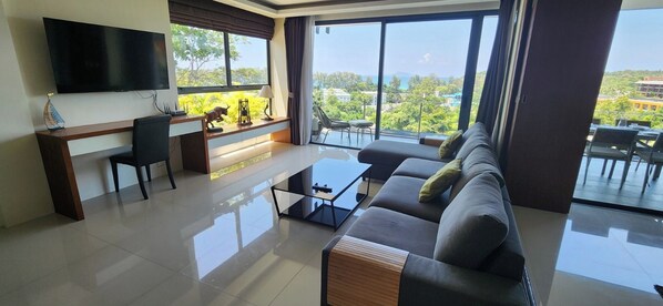 En moderne stue med et fladskærms-tv, en sofa, et sofabord og en balkon med udsigt.
