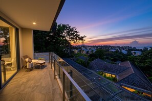 Ein Balkon mit Blick auf eine Stadtlandschaft in der Dämmerung.