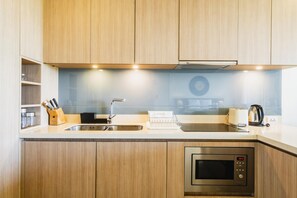 Eine moderne Küche mit Holzschränken, Edelstahlgeräten und einem eingebauten Backofen.