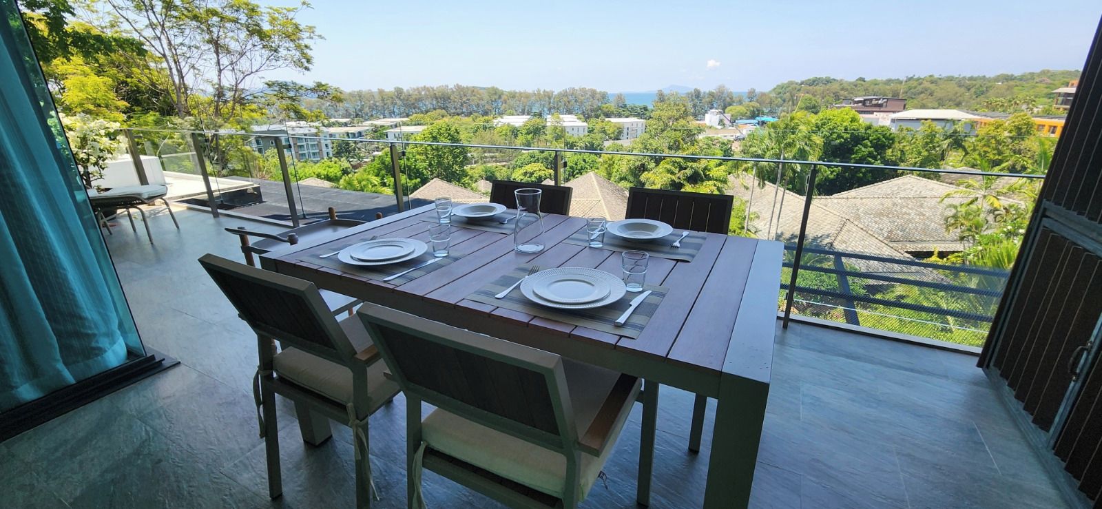 A dining table set for four with a view of a residential area and greenery.